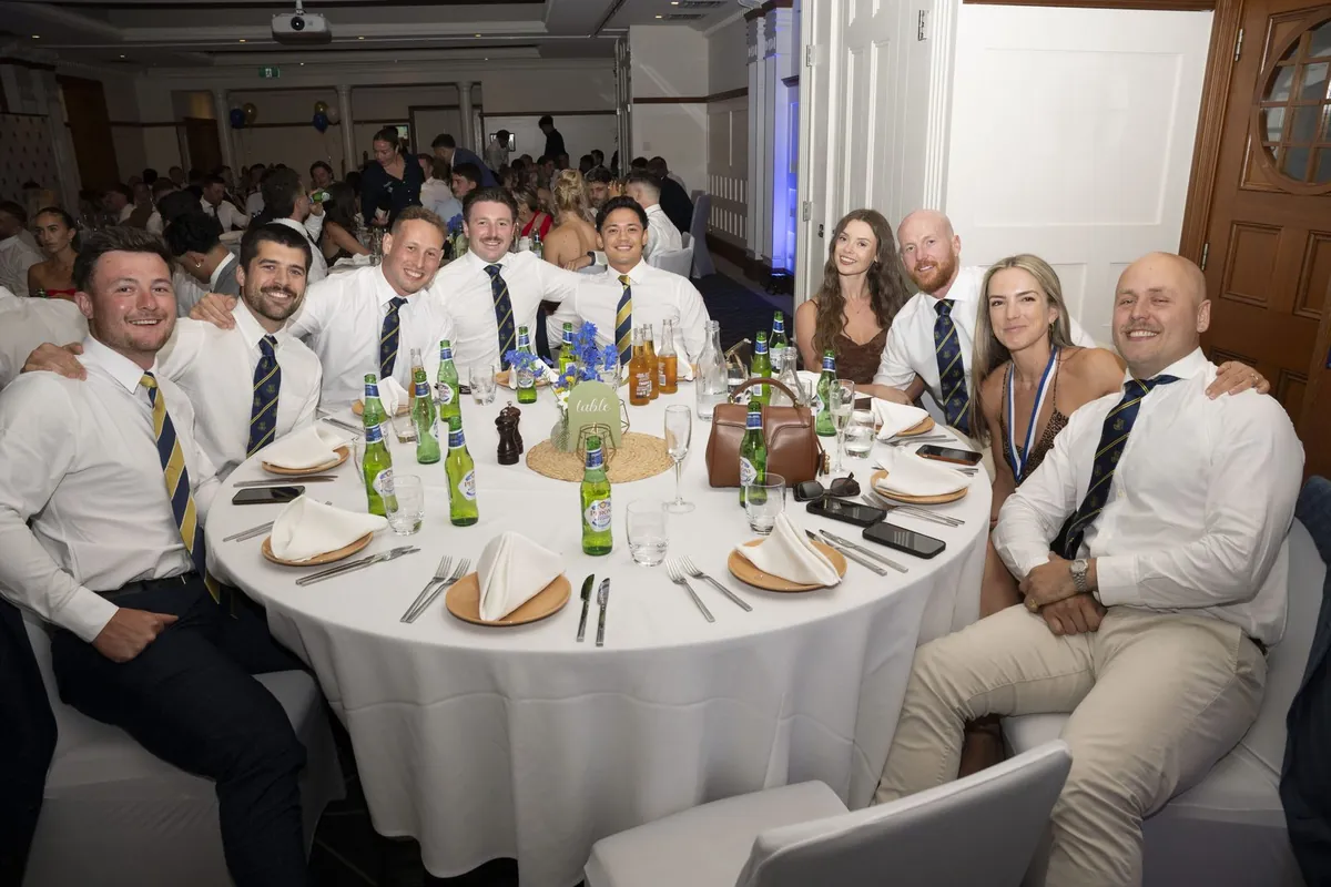 Members and guests in shirts, blazers and club ties seated around a formally laid dinner table in the banquet hall.